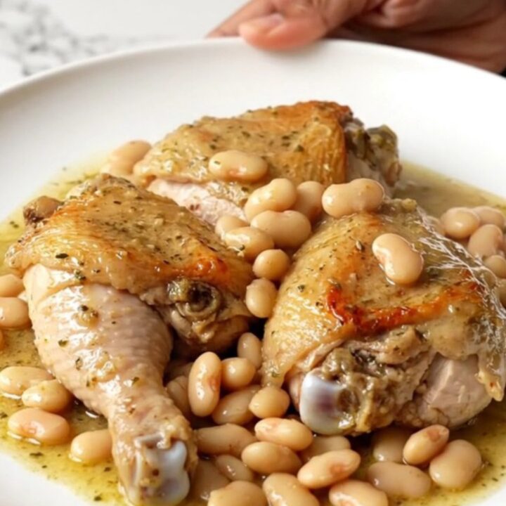 A slow cooker filled with creamy chicken thighs and butter beans in a rich garlic sauce.