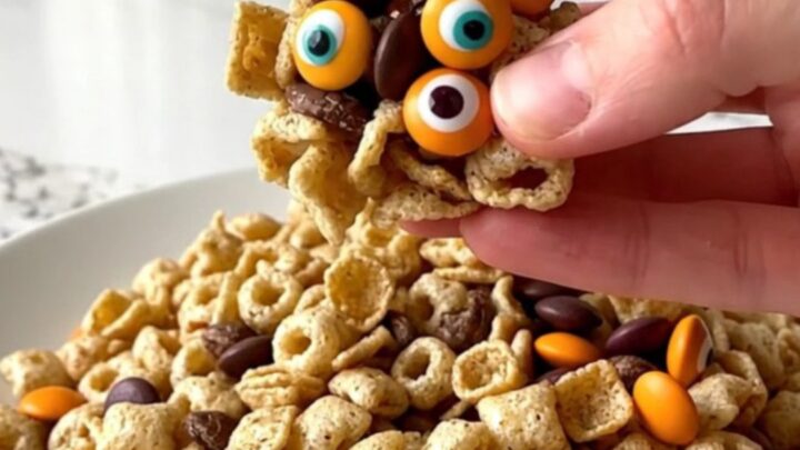 A colorful monster snack mix served in a white bowl with orange and purple candies visible.