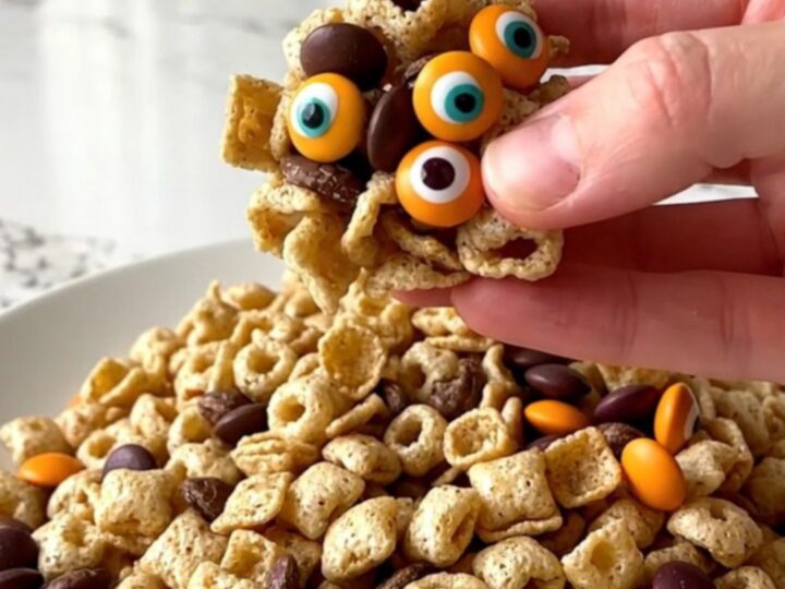 A colorful monster snack mix served in a white bowl with orange and purple candies visible.