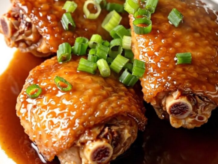 A high-angle shot of tender, braised chicken thighs in a slow cooker with a rich, dark shoyu glaze.