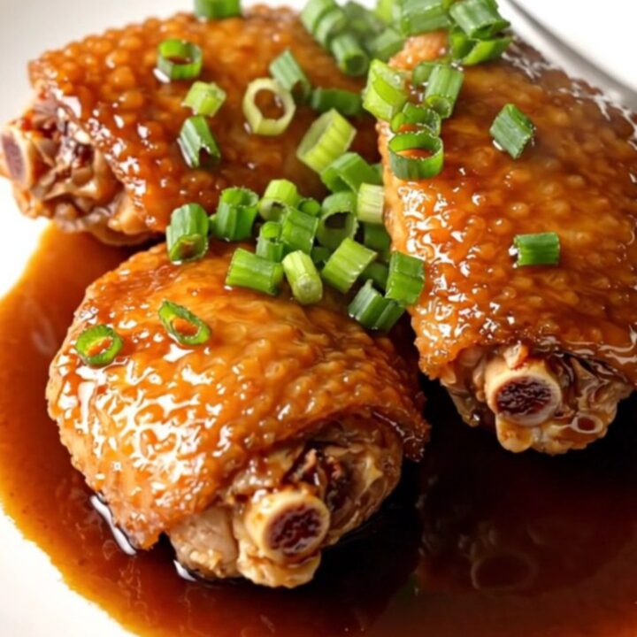 A high-angle shot of tender, braised chicken thighs in a slow cooker with a rich, dark shoyu glaze.