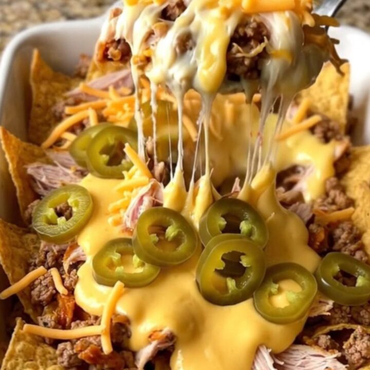 A top-down view of a rectangular baking dish filled with tortilla chips, seasoned turkey, queso, and jalapenos.