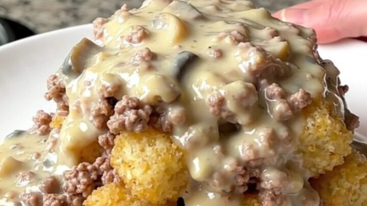 A hearty scoop of creamy turkey and potato tot hotdish served on a plain white plate.