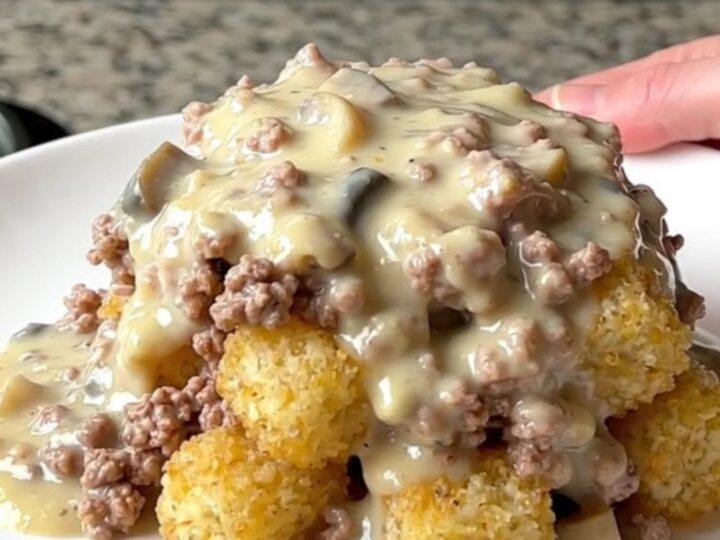 A hearty scoop of creamy turkey and potato tot hotdish served on a plain white plate.