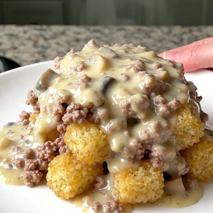 A hearty scoop of creamy turkey and potato tot hotdish served on a plain white plate.