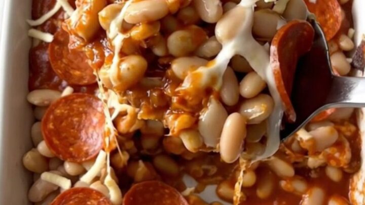 A top-down view of a rectangular baking dish filled with white beans, marinara, mozzarella, and pepperoni slices.