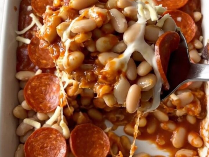 A top-down view of a rectangular baking dish filled with white beans, marinara, mozzarella, and pepperoni slices.