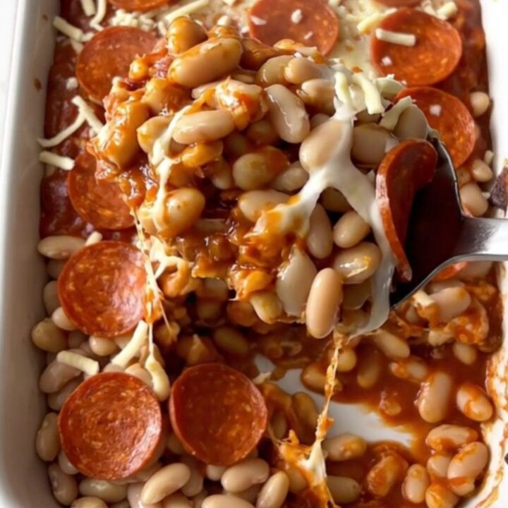 A top-down view of a rectangular baking dish filled with white beans, marinara, mozzarella, and pepperoni slices.