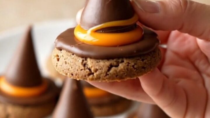 A plate of finished witch hat cookies with orange candy and chocolate drops.