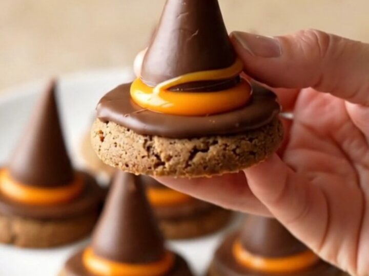 A plate of finished witch hat cookies with orange candy and chocolate drops.