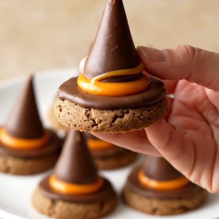 A plate of finished witch hat cookies with orange candy and chocolate drops.