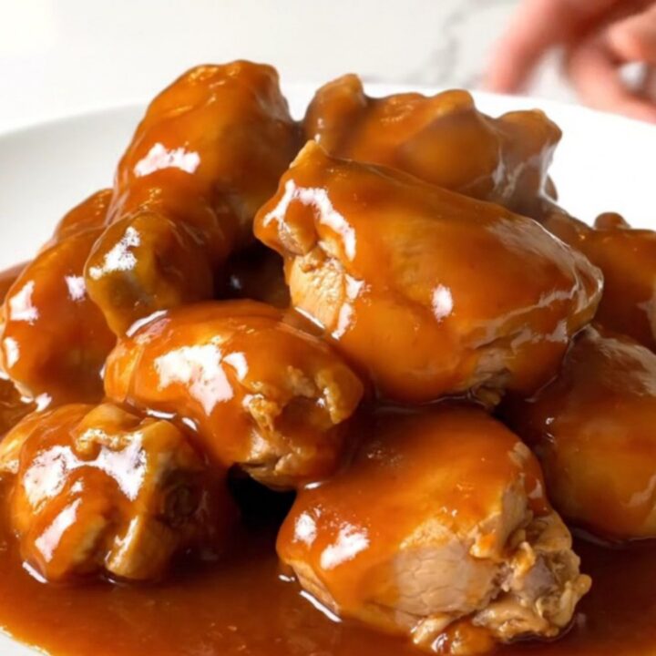 A close-up of slow cooker sweet fire chicken served on a white plate with visible pineapple and pepper chunks.