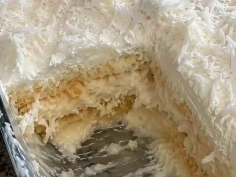 A decadent, creamy slice of no-bake coconut cake being lifted from a glass dish.
