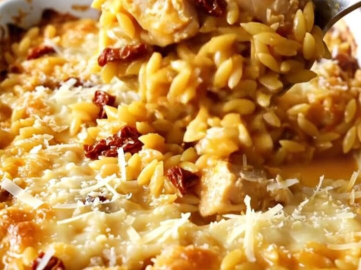 A top-down view of a creamy Chicken Orzo Bake in a ceramic dish, golden and bubbly.