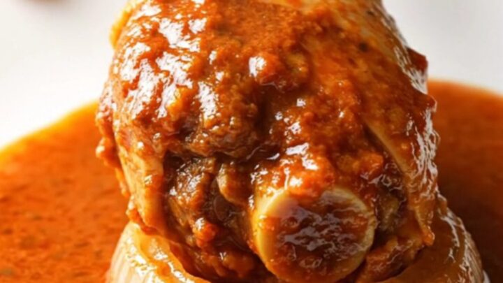A close-up of tender, shredded turkey birria in a rich red sauce served in a rustic bowl.