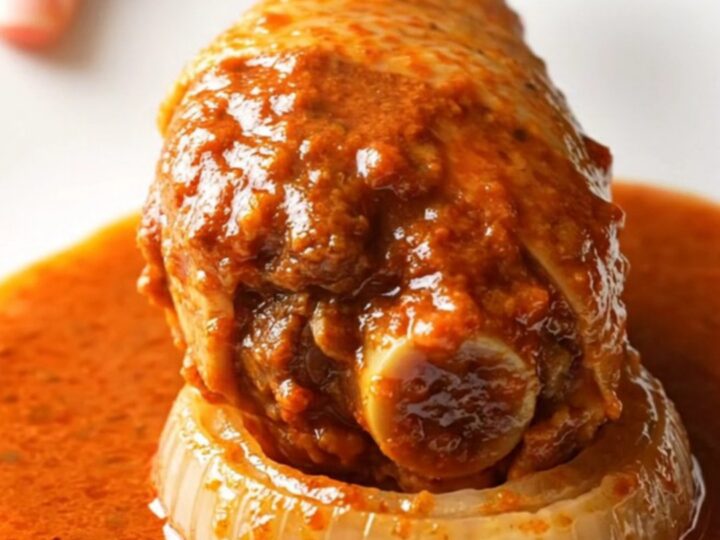 A close-up of tender, shredded turkey birria in a rich red sauce served in a rustic bowl.