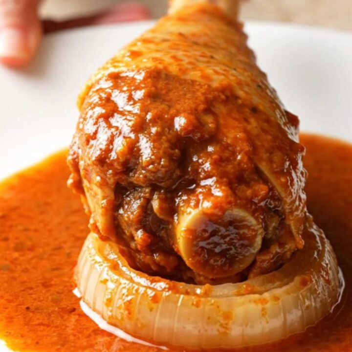 A close-up of tender, shredded turkey birria in a rich red sauce served in a rustic bowl.