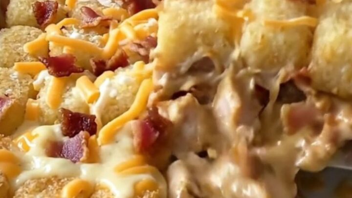 A golden brown chicken bacon ranch potato tot casserole in a white baking dish.