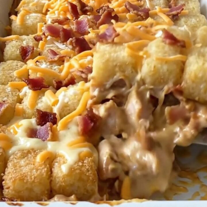 A golden brown chicken bacon ranch potato tot casserole in a white baking dish.