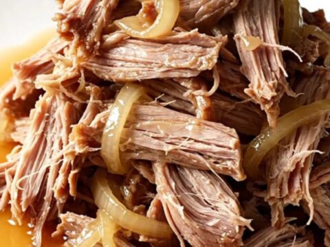 A close-up of tender, shredded slow cooker sweet tea pulled pork in a rustic stoneware bowl.