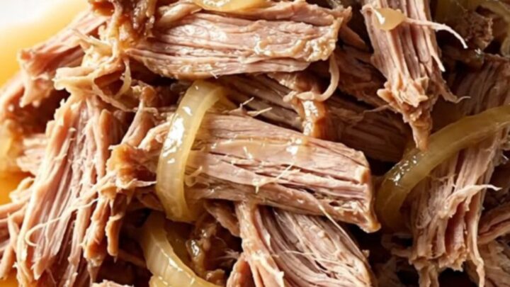 A close-up of tender, shredded slow cooker sweet tea pulled pork in a rustic stoneware bowl.
