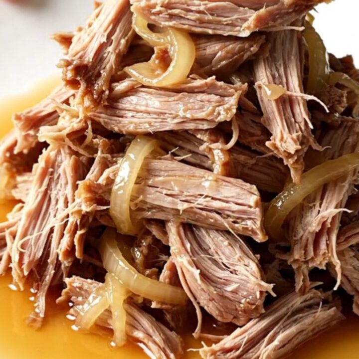 A close-up of tender, shredded slow cooker sweet tea pulled pork in a rustic stoneware bowl.