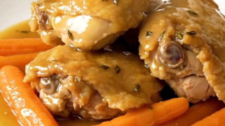 A close-up of tender chicken thighs and bright orange baby carrots in a honey thyme glaze.