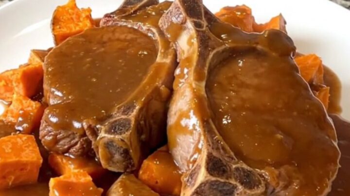 Close up of tender pork chops and sweet potato cubes glazed in a rich brown sugar sauce in a slow cooker.