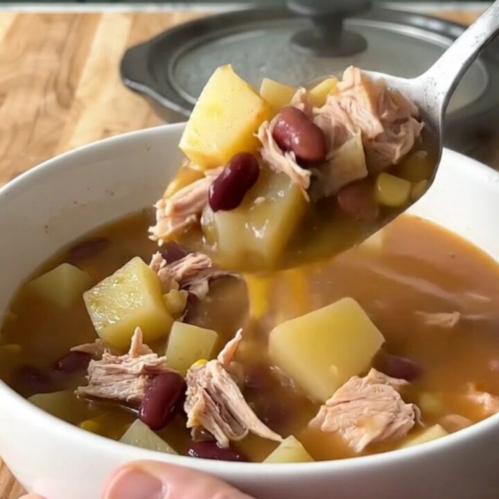 A close-up of a bowl of Cowboy Soup with ground turkey, potatoes, and beans in a rich tomato broth.
