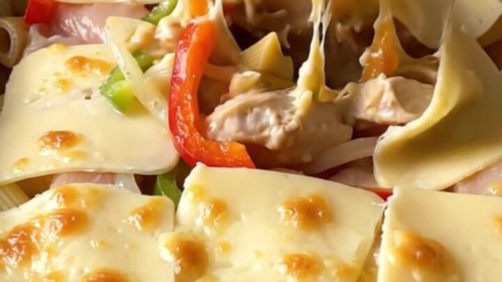 A top-down view of a rectangular baking dish filled with creamy chicken Philly pasta topped with melted provolone.