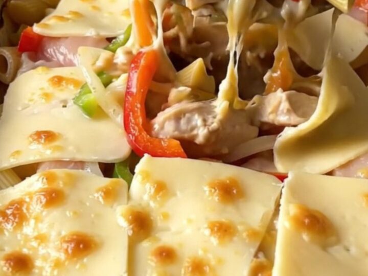 A top-down view of a rectangular baking dish filled with creamy chicken Philly pasta topped with melted provolone.