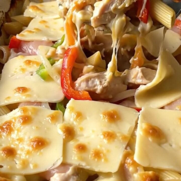 A top-down view of a rectangular baking dish filled with creamy chicken Philly pasta topped with melted provolone.