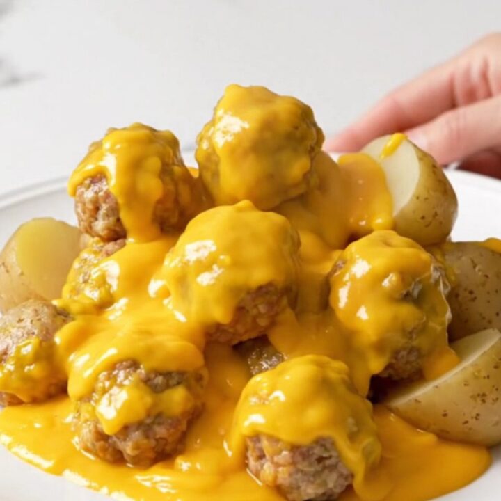 A top-down view of the slow cooker filled with turkey meatballs and halved baby potatoes covered in a creamy cheddar sauce.