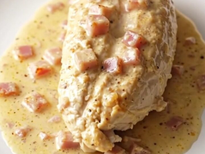 A serving of creamy slow cooker chicken cordon bleu with ham and melted Swiss cheese on a plate.