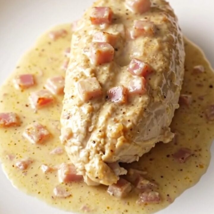 A serving of creamy slow cooker chicken cordon bleu with ham and melted Swiss cheese on a plate.