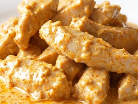 A close-up of creamy Crockpot Chicken Lazone in a slow cooker, showing tender chicken coated in a rich
