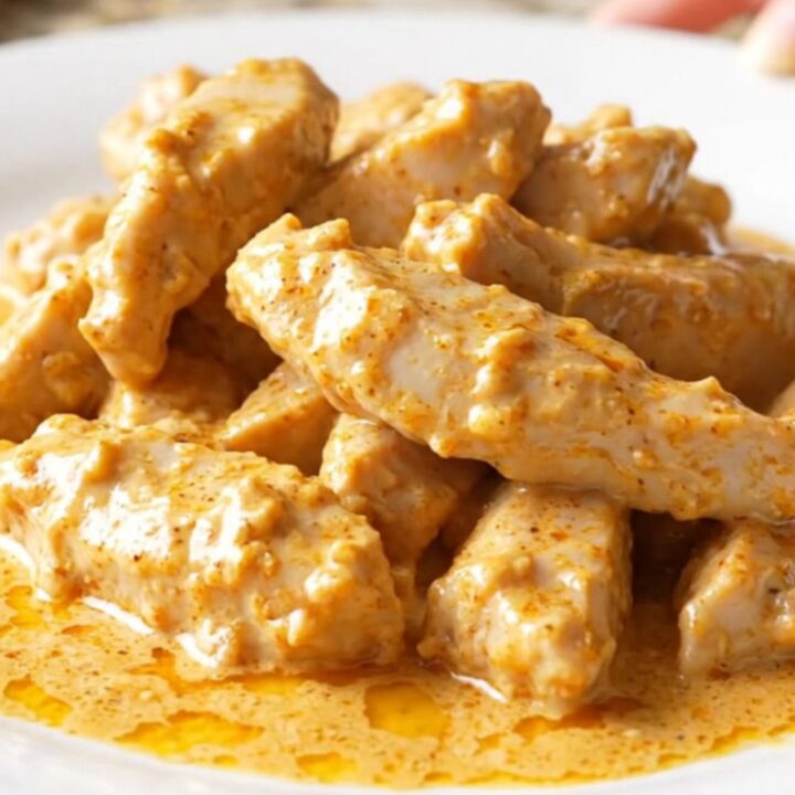 A close-up of creamy Crockpot Chicken Lazone in a slow cooker, showing tender chicken coated in a rich