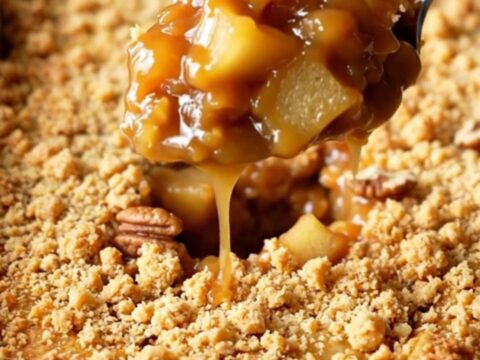 A golden, bubbling salted caramel apple pecan dump cake in a rectangular baking dish.