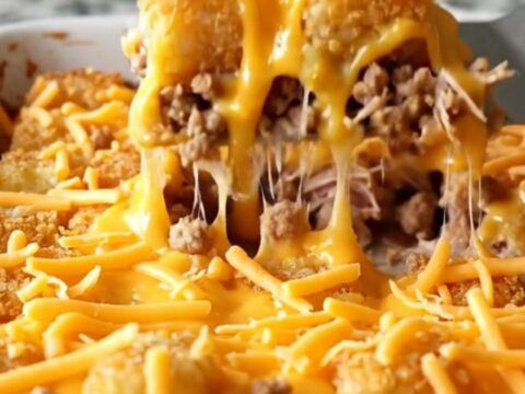 A top-down view of a golden, crispy cheeseburger potato tot bake in a white ceramic dish.