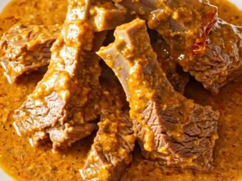 A close-up of tender beef chuck cubes in a rich, creamy sun-dried tomato sauce inside a slow cooker.