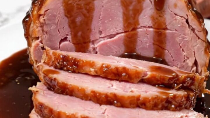 A beautifully glazed spiral-cut ham sitting in a slow cooker, glistening with a sweet, dark root beer sauce.