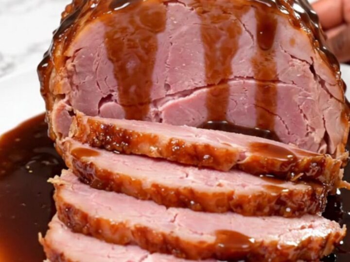 A beautifully glazed spiral-cut ham sitting in a slow cooker, glistening with a sweet, dark root beer sauce.