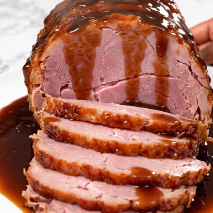 A beautifully glazed spiral-cut ham sitting in a slow cooker, glistening with a sweet, dark root beer sauce.