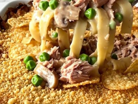 A golden, bubbly tuna noodle bake in a white ceramic dish sitting on a white quartz countertop.