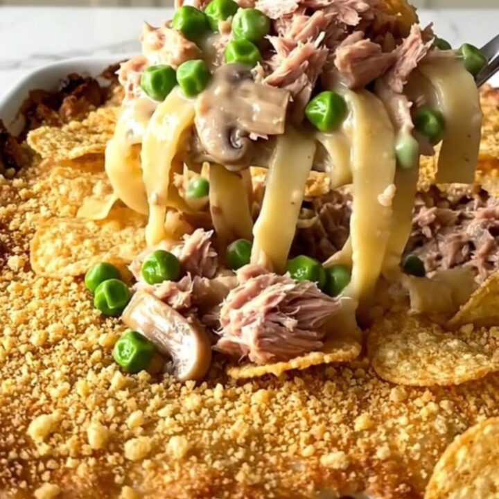 A golden, bubbly tuna noodle bake in a white ceramic dish sitting on a white quartz countertop.