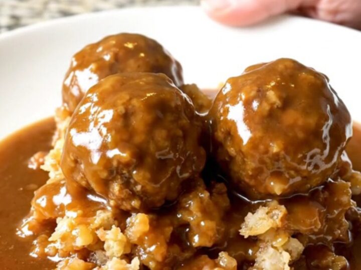 A slow cooker filled with turkey meatballs and stuffing covered in rich brown gravy.