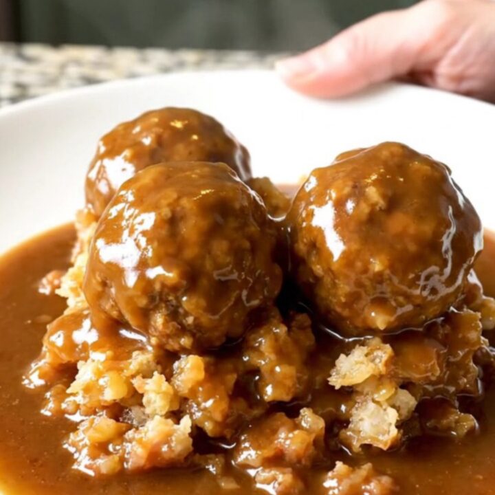 A slow cooker filled with turkey meatballs and stuffing covered in rich brown gravy.