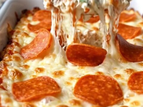 A delicious, creamy pepperoni pizza dip in a white baking dish, topped with bubbling mozzarella and pepperoni.
