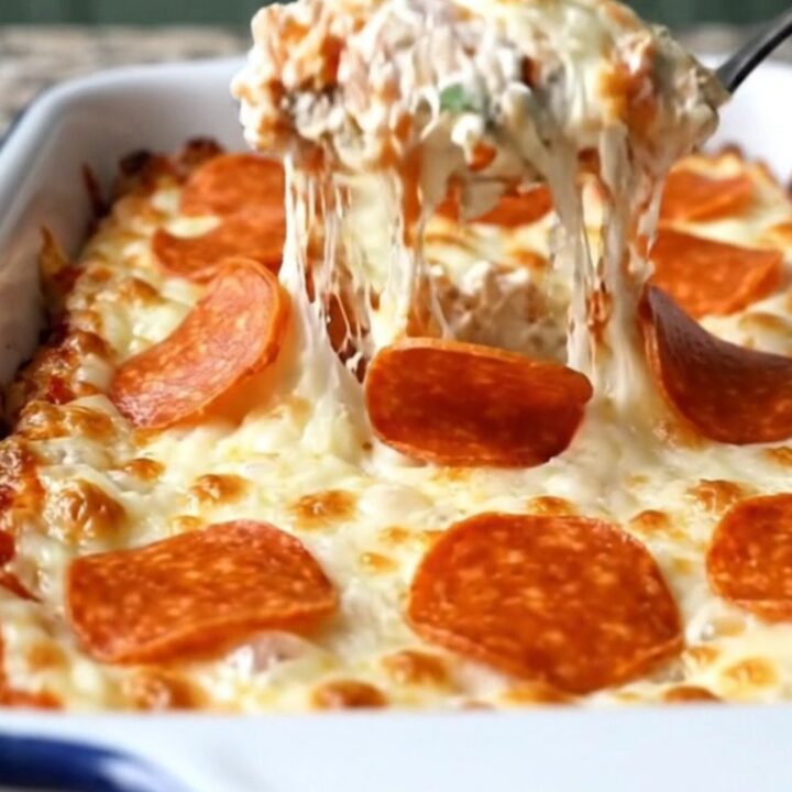 A delicious, creamy pepperoni pizza dip in a white baking dish, topped with bubbling mozzarella and pepperoni.