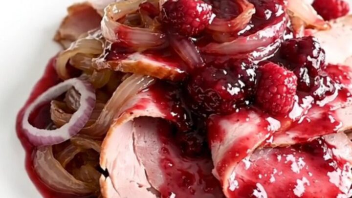 A spiral-sliced ham in a slow cooker topped with raspberry preserves and smoky chili powder.
